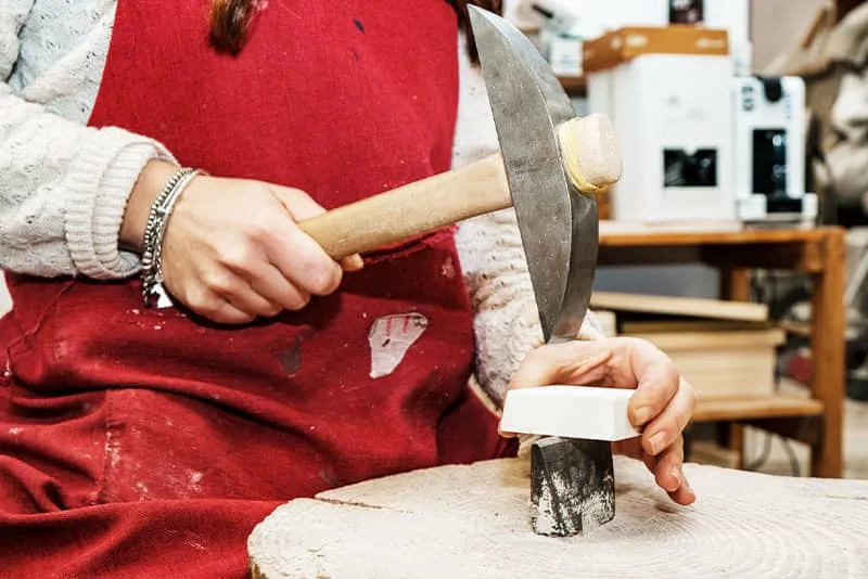 Hands using a hammer and hardie during a mosaic workshop